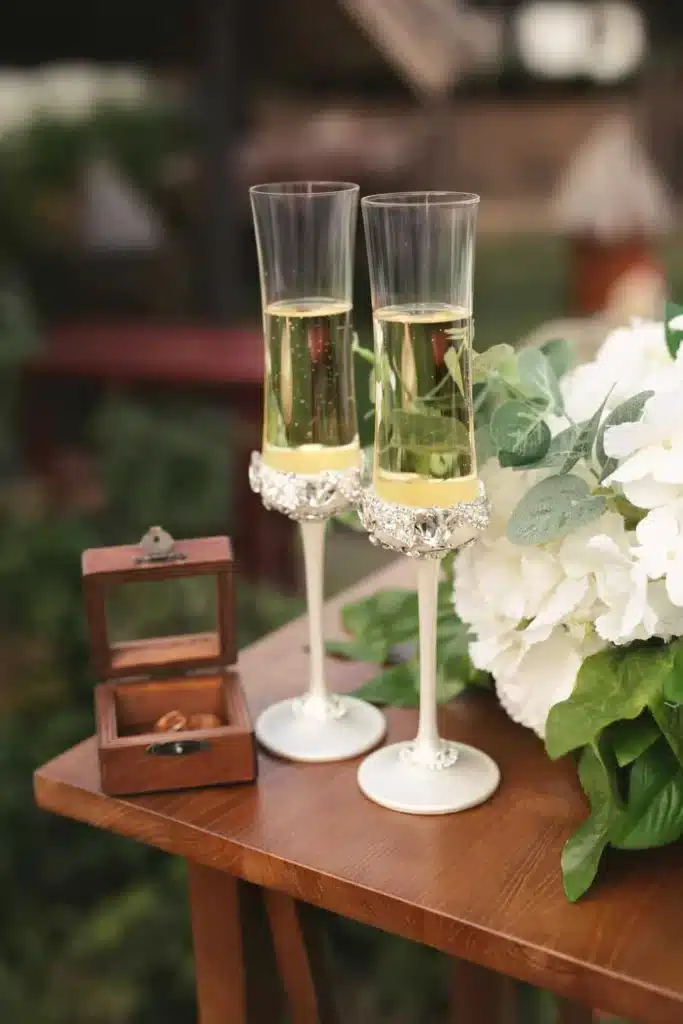 Two champagne glasses with wedding rings on a table with flowers